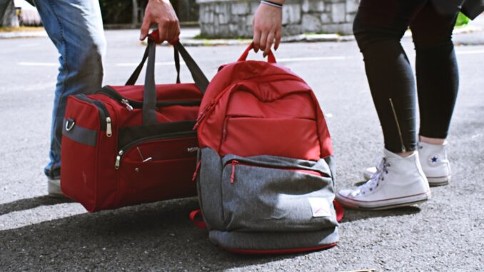 To mennesker stiller røde tasker på jorden